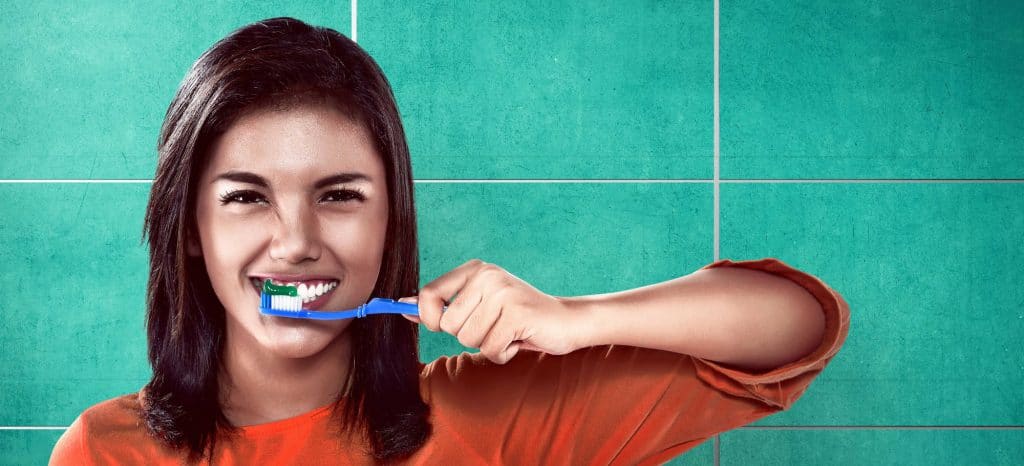 College student brushing her teeth on the bathroom